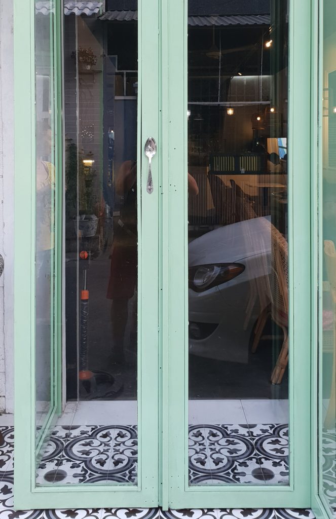 Origineller Türgriff eines Cafés an der lebendigen De Tham Straße